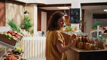 souriant femme dans zéro déchets supermarché en utilisant papier sac à achat garde-manger agrafes, avoir recommandations de utile fournisseur. végétalien client dans local épicerie magasin aidé par vendeur avec Info video