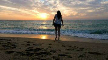 contento mujer jugando y corriendo desde el agua en el playa a el amanecer. viajar, relajación y vacaciones video