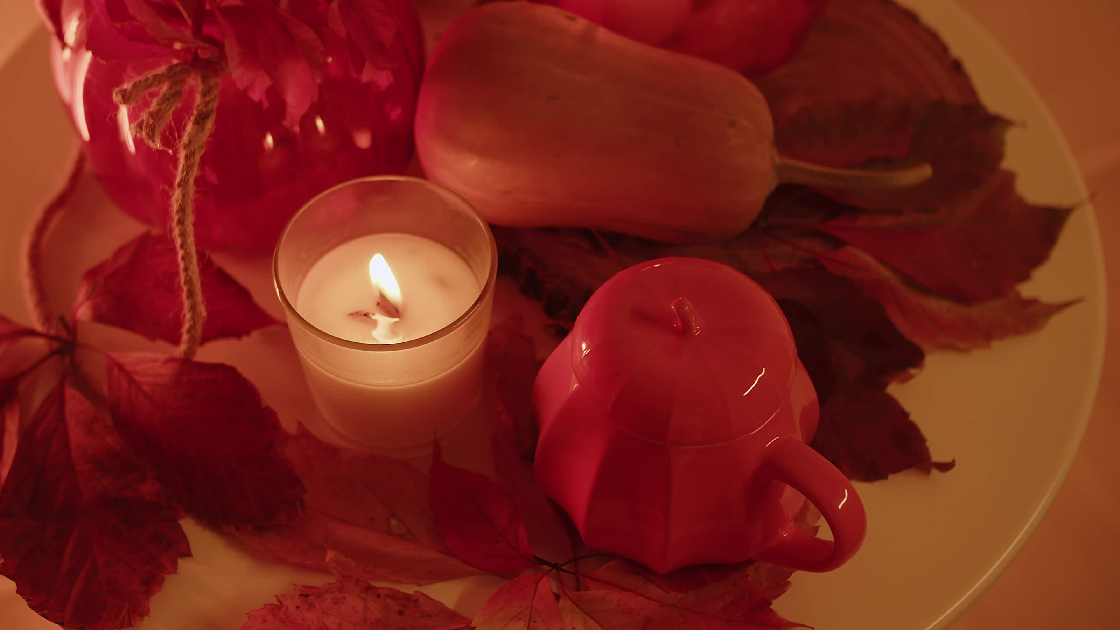 Fall decor on a table with a burning candle and bouncing flames