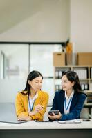 Two Asian businesswoman and man discuss investment project working and planning strategy with tablet laptop computer in modern office. photo