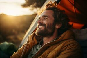 Portrait of man looking at camera while near camping tent at sunset AI generated photo