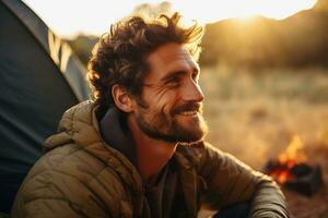 Portrait of man looking at camera while near camping tent at sunset AI generated photo