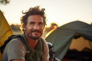 Portrait of man looking at camera while near camping tent at sunset AI generated photo