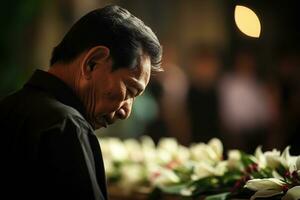 Elderly asian man with funeral sorrow and flowers in church AI generated photo