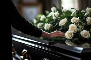 Closeup of a woman's hand placing a bouquet of white roses in a coffin.Funeral Concept AI generated photo