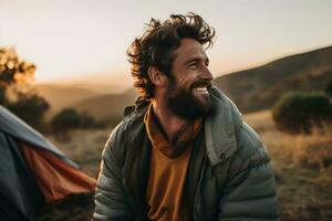 Portrait of man looking at camera while near camping tent at sunset AI generated photo