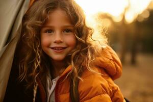 Portrait of cute little girl at camera while standing near camping tent at sunset AI generated photo