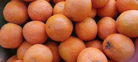 fresh orange fruits with leaves as background, top view photo