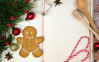 Book for recipes, Christmas decor and gingerbread man on the wooden table. Christmas baking. Close-up. Top view. Copy space. photo