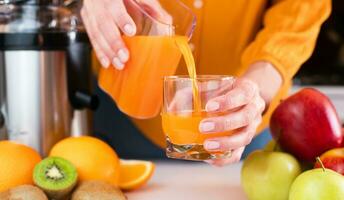 mujer manos verter recién preparado sabroso y sano jugo dentro un vaso. sano Fruta jugos a hogar. de cerca. selectivo enfocar. foto