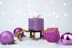 Christmas composition with decorative wooden sleigh, gift boxes, christmas balls on snowy background. New Year card. Close-up. Selective focus. photo