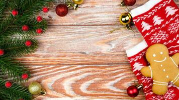 Navidad antecedentes con decoraciones, abeto sucursales, rojo calcetines y un pan de jengibre hombre en de madera mesa. plano parte superior vista. Copiar espacio. selectivo enfocar. foto
