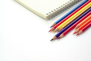 Focus of colored pencils or pastel lined up and blur graph book on white background. Learning, study and presentation concept. photo