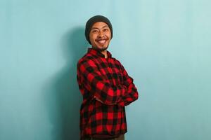 Confident young Asian man is looking at the camera with his arms crossed isolated on blue background photo