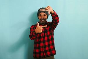 Excited Young Asian man is making a picture frame gesture, isolated on a blue background photo