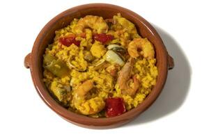 Seafood paella, isolated on a white background. Seafood paella tapa, served in a clay bowl. Spanish food concept. photo