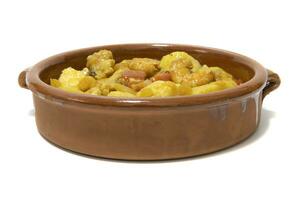 Potato stew with cod, served in a clay bowl. Isolated on white background. Spanish food concept. photo