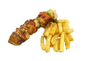 A skewer of meat and vegetables, accompanied with pommes frites. Isolated on a white background. photo