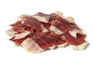 Sliced Iberian Serrano ham isolated on white background. Iberian serrano ham is a Spanish delicacy,famous for its smoky flavor and tender, salty texture, the richness of the Iberian culinary tradition photo