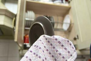 A man drying a plate with a cloth, to put it on the dish rack. Home life concept. photo