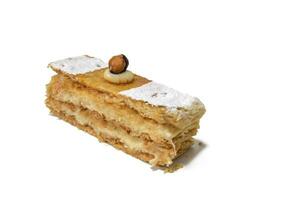 A sweet puff pastry filled with cream and a hazelnut on top, isolated on a white background. . photo