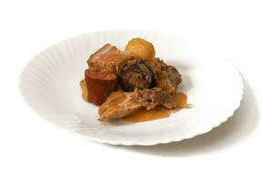 A plate of Pringa, isolated on a white background. The pringa in a chickpea stew is a rich mix of chorizo, ham and other flavorful meats, adding a hearty, savory essence to the comforting dish. photo