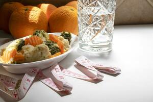 A tape measure is on a table with oranges. Diets concept. photo