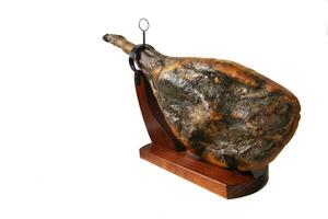 A leg of Iberian serrano ham isolated on white background. Iberian serrano ham is a Spanish delicacy, famous for its smoky flavor and tender, salty texture, the richness of the Iberian culinary photo