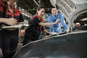 Asian male professional automotive supervisor advises and inspects a mechanic worker woman about liquid engine oil at car garage, service maintenance, and fix specialist occupations auto industry. photo