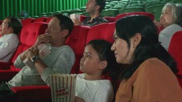 divers gens dans théâtre. asiatique famille et multiracial public sont effrayé de en train de regarder Thriller en francais et horreur cinéma, effrayé ensemble sur film organiser, et divertissement mode de vie avec film art montrer. video