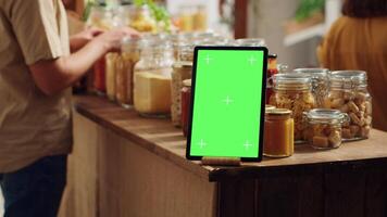 Mockup tablet with empty copy space used as commercial sign in zero waste supermarket, close up. Isolated screen device acting as promotional message in food store with biodegradable packaged products video