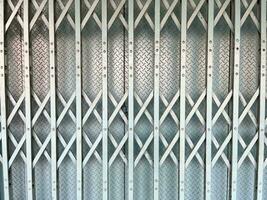 White or light gray colored metal folding door gate texture in front of store background. photo