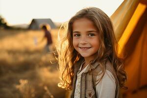 Portrait of cute little girl at camera while standing near camping tent at sunset AI generated photo