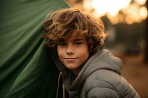 Portrait of a cute boy looking at camera while near his tent in nature AI generated photo