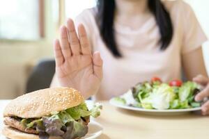 belleza cuerpo femenino delgado confundir hamburguesa. mujer en restaurante logra el objetivo de pérdida de peso para una vida saludable, loca por la delgadez, cintura delgada, nutricionista. dieta, forma del cuerpo. foto