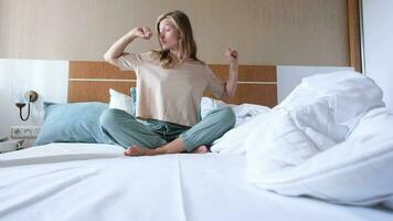 Young woman waking up and stretching in the morning in hotel room video