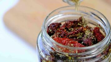 preparing preserves with sun dried tomatoes, filling the bowl with spices and olive oil video