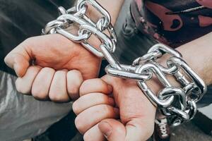 Men's hands are chained in thick steel shackles photo