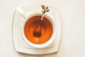 White cup with saucer and golden spoon and tea leaves photo