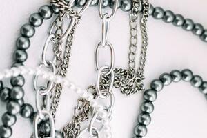 A necklace of gray beads with chain decorations on a white aesthetic background. photo