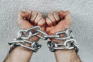 Men's hands are chained in thick steel shackles photo