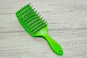 Massage light green hair brush on a wooden background. photo