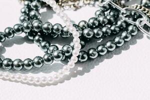 A necklace of gray beads with chain decorations on a white aesthetic background. photo