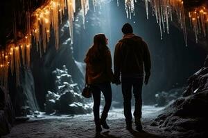 Couple exploring icy cave with hanging icicles background with empty space for text photo