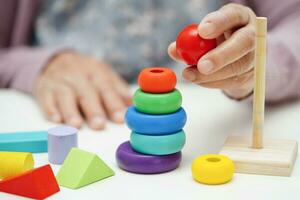 Asian elderly woman playing puzzles game for dementia prevention, Alzheimer disease. photo