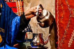 a man in blue robes pouring tea photo