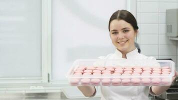 Professional confectioner smiling holding out tray full of macaroons to the camera video