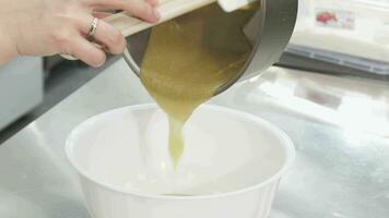 pastelaria chefe de cozinha derramando quente creme a partir de uma panela para dentro uma tigela video