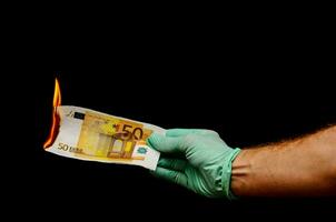 Hand holding a banknote on fire photo