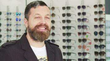 Cheerful mature man smiling to the camera while buying sunglasses video